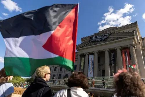 علم فلسطيني يُرفع في احتجاج أمام متحف بروكلين، مع لافتات تدعو إلى الحرية لفلسطين، تعبيرًا عن التضامن مع القضية الفلسطينية.