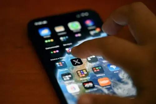 إصبع يضغط على أيقونة تطبيق X على هاتف ذكي، في سياق قرار المحكمة العليا البرازيلية برفع الحظر عن المنصة.