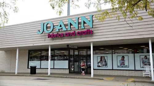 واجهة متجر Joann للأقمشة والحرف، مع لافتة ملونة تحمل اسم المتجر، وامرأة تدخل المتجر، تعكس التحديات التي تواجهها الشركة.