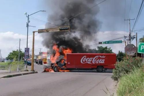 شاحنة Coca-Cola مشتعلة في كولياكان، مع تصاعد الدخان الأسود في السماء، تعكس مشهد العنف المستمر في المدينة.