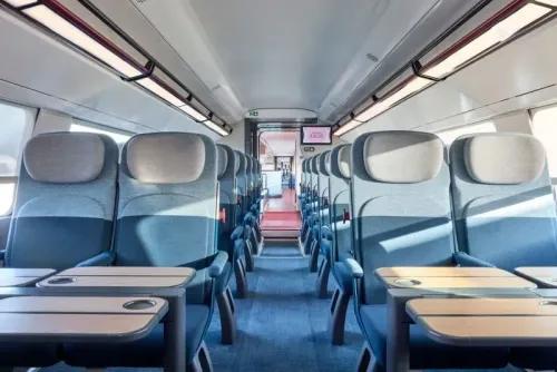 تصميم داخلي حديث لعربة قطار TGV الجديدة، مع مقاعد مريحة وطاولات، يعكس الابتكار في تجربة السفر الفائق السرعة.