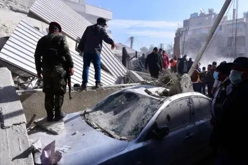 دخان يتصاعد من مبنى مدمر في دمشق، حيث يتجمع رجال الإنقاذ حول سيارة مغطاة بالأنقاض بعد هجوم جوي أسفر عن مقتل 13 شخصًا.