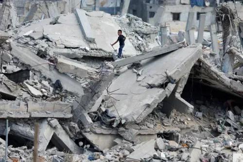 طفل يقف على أنقاض مبنى مدمر في غزة، يعكس آثار النزاع المستمر والمعاناة الإنسانية.