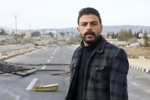 رجل يقف في وسط طريق مهدم في القنيطرة، تظهر خلفه آثار الدمار والخراب الناتج عن التوغل الإسرائيلي، مع تعبير عن القلق وعدم اليقين.