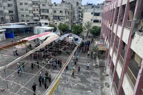 مدرسة أبو عاصي في مخيم الشاطئ للاجئين، حيث يتجمع النازحون الفلسطينيون بعد غارة إسرائيلية، مع آثار الدمار في الخلفية.