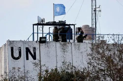 جنود من قوات اليونيفيل في لبنان يقفون على سطح مركزهم، مع العلم الأزرق للأمم المتحدة يرفرف في الخلفية، في ظل تصاعد التوترات.