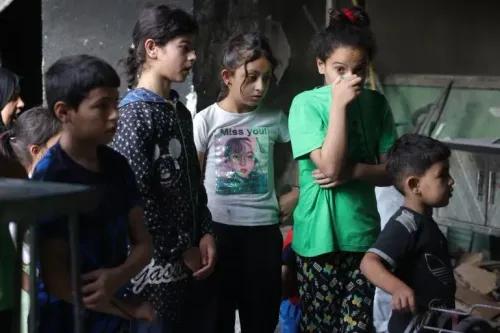 مجموعة من الأطفال في وضع حزين، يظهرون مشاعر القلق في بيئة تضررت من الصراع في فلسطين. تعكس الصورة الأزمة الإنسانية المستمرة.