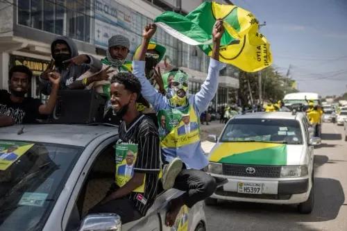 أنصار حزب \"كولميي\" الحاكم يحتفلون في شوارع هرجيسا، يرتدون قمصاناً خضراء وصفراء، مع لافتات انتخابية، قبل الانتخابات العامة في أرض الصومال.