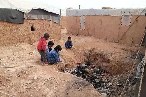 أطفال يلعبون بالقرب من حفرة في مخيم الركبان للنازحين، الذي أغلق مؤخرًا بعد سنوات من المعاناة في الصحراء السورية.