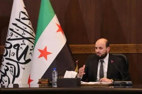رئيس الوزراء السوري المؤقت محمد البشير يتحدث في اجتماع، مع العلم السوري خلفه، وسط تعهدات بحماية حقوق الأقليات وتحقيق الأمن.
