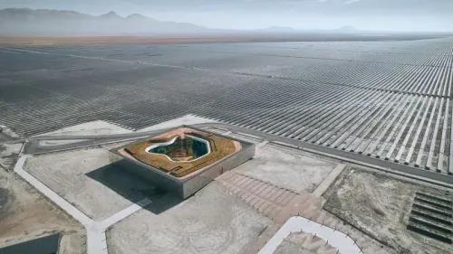 مشروع معماري مبتكر يبرز مركز التحكم في محطة توليد الطاقة الشمسية، محاط بصفوف من الألواح الشمسية في منطقة صحراوية.
