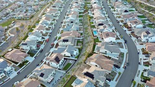 مجموعة من المنازل الحديثة في حي سكني، توضح تصميمات متنوعة وأسقف مائلة، تعكس ارتفاع الطلب على الإسكان في السوق.