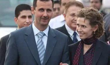 بشار الأسد وزوجته أسماء في مناسبة رسمية، يعكسان صورة السلطة وسط حشد من الناس، في سياق الحديث عن الهروب من العدالة.