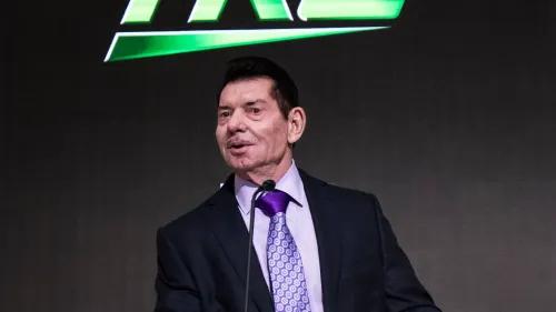 فينس مكمان يتحدث في مؤتمر صحفي، مرتديًا بدلة رسمية، مع شعار WWE خلفه، بعد تسوية قانونية بملايين الدولارات.