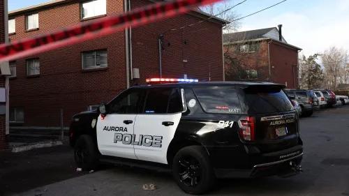 سيارة شرطة أورورا متوقفة أمام مجمع سكني، مع وجود شريط أمني، في إطار تحقيق حول جريمة اختطاف وسرقة.